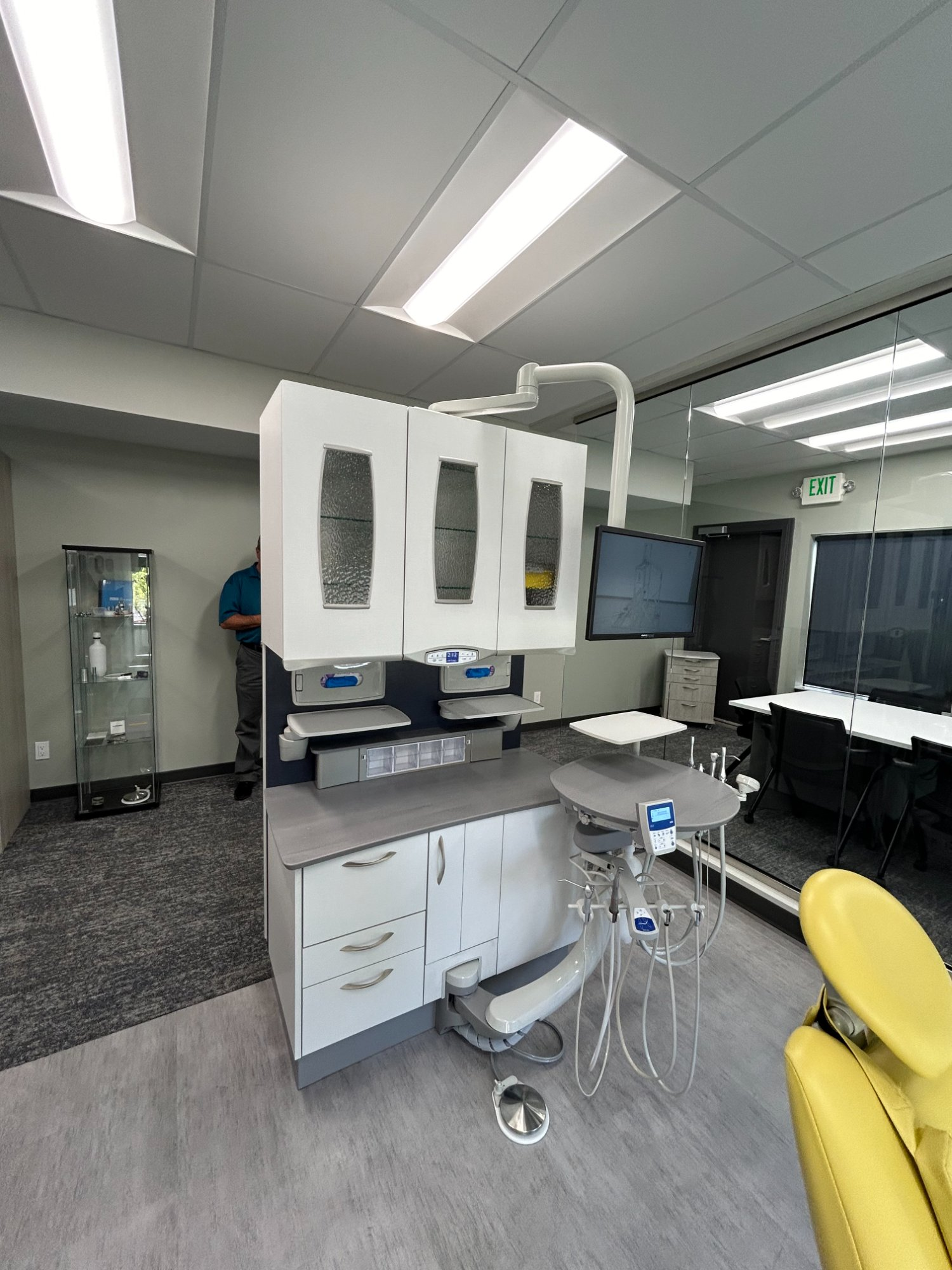 A-dec showroom-style operatory with dual handpiece delivery, monitor, and integrated cabinetry