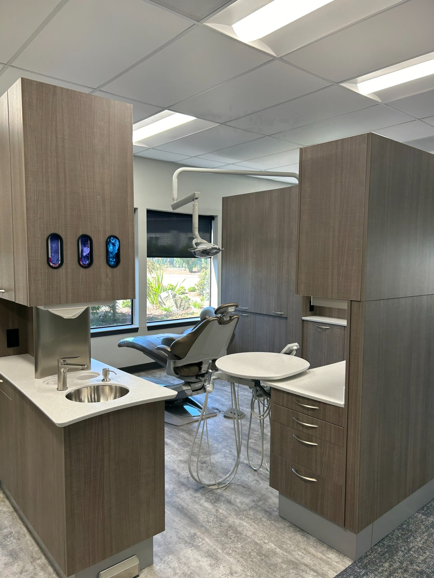 Completed A-dec operatory with warm wood cabinetry, integrated sink, and overhead light