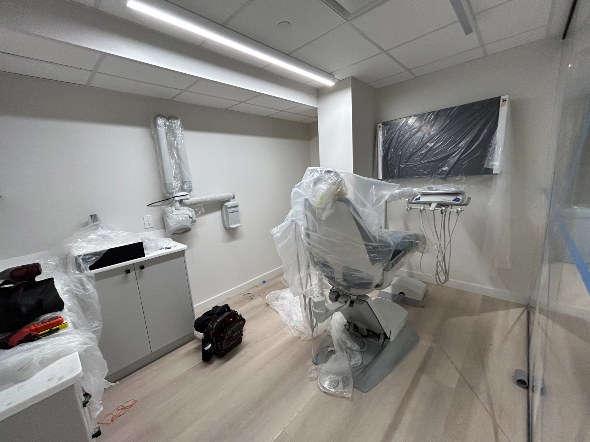 Dental chair with overhead light and delivery system being installed in modern gray operatory