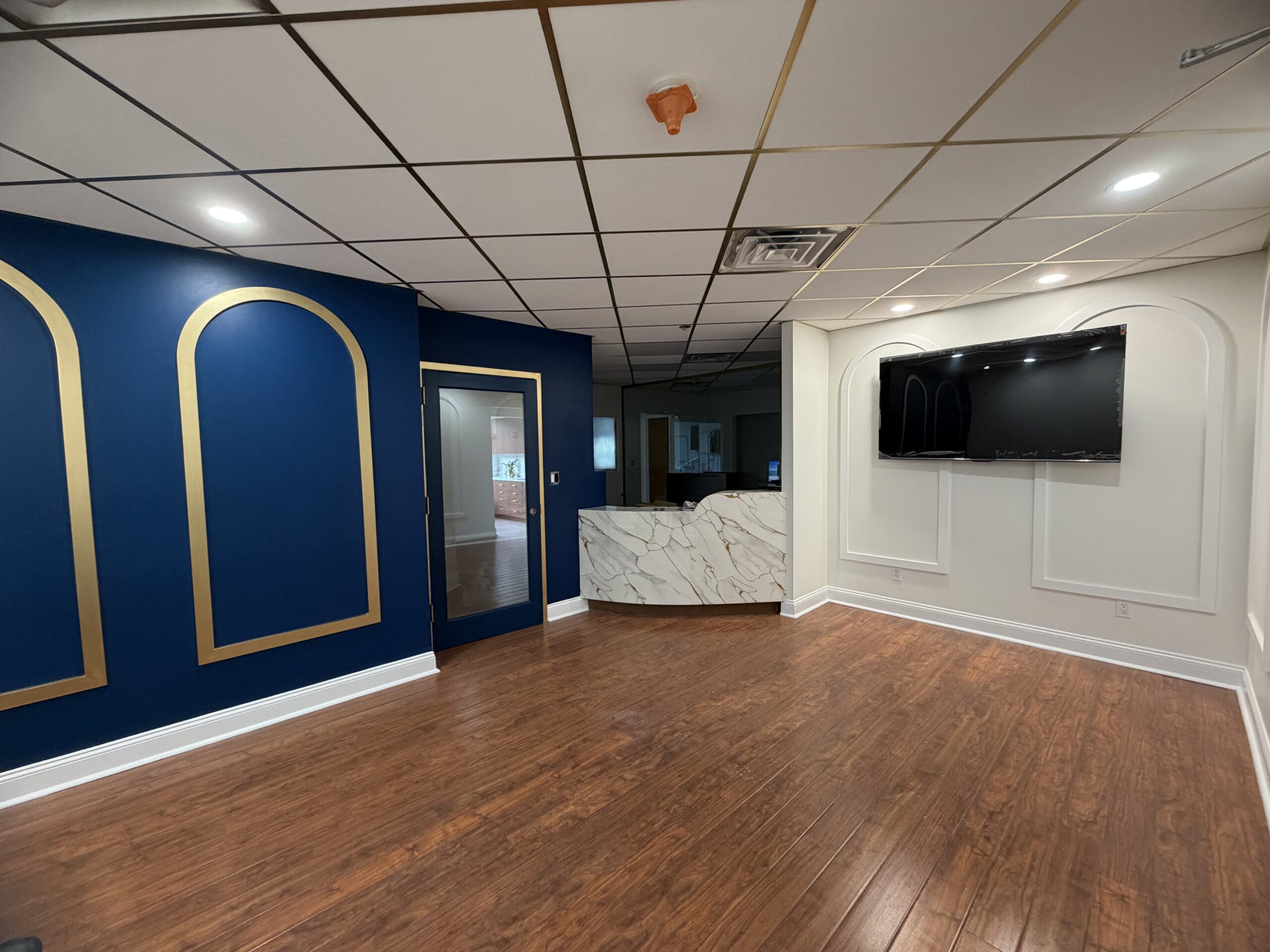 Custom curved reception desk clad in calacatta marble-look pvc with a backlit gold base in a Scarsdale dental office